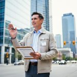 A Calgary worker holding employment-related documents outside a modern office building, representing workplace rights and access to free help.